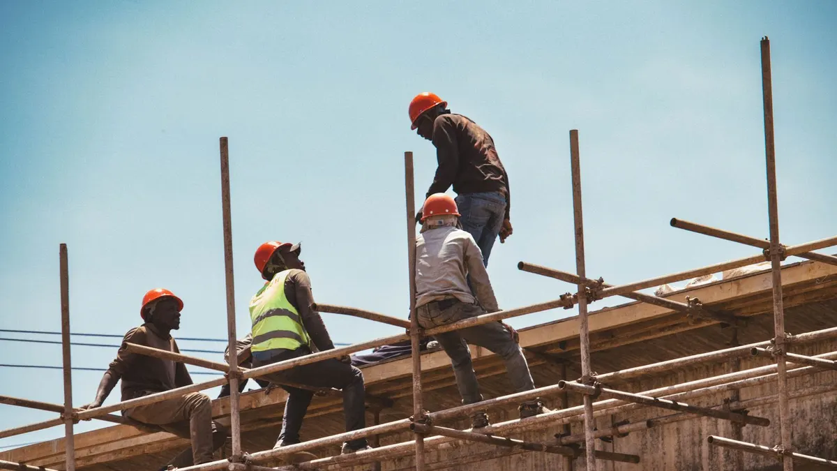 Construction workers wearing safety gear on scaffolding at a commercial jobsite