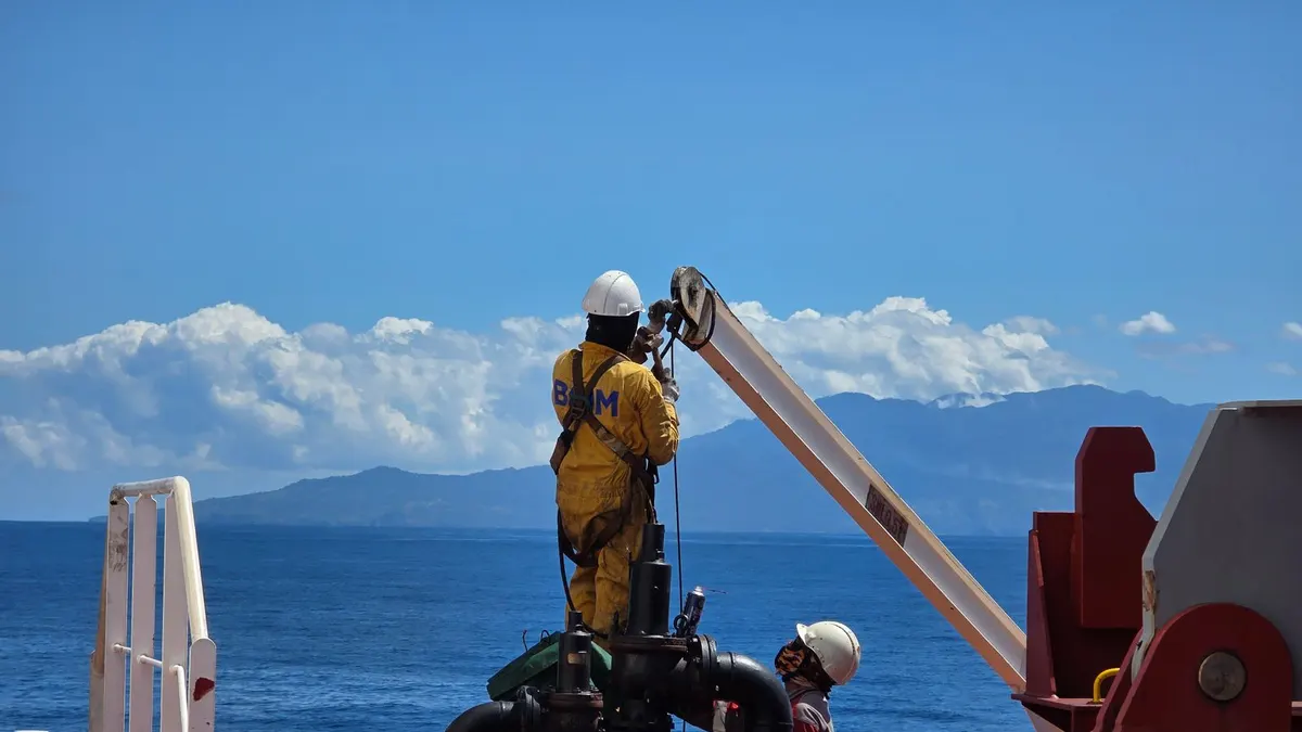 Field service workers in safety gear operating equipment on an offshore energy vessel